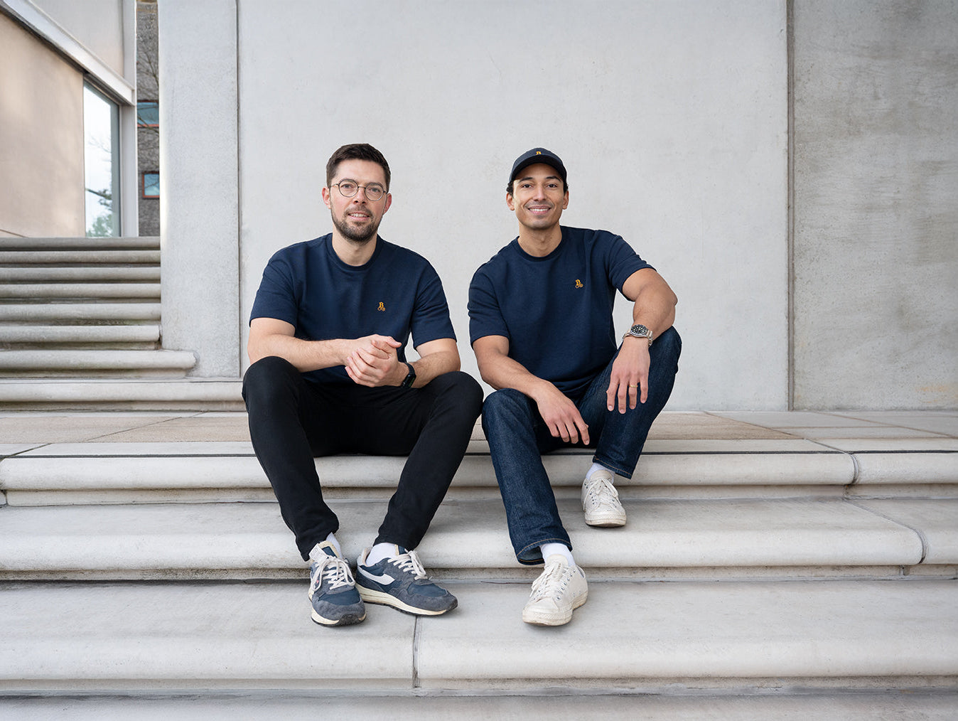 Tobi och Henry från Bitcoin21 på betongtrappor i Hamburg, båda i Bitcoin T-shirt med broderad logotyp