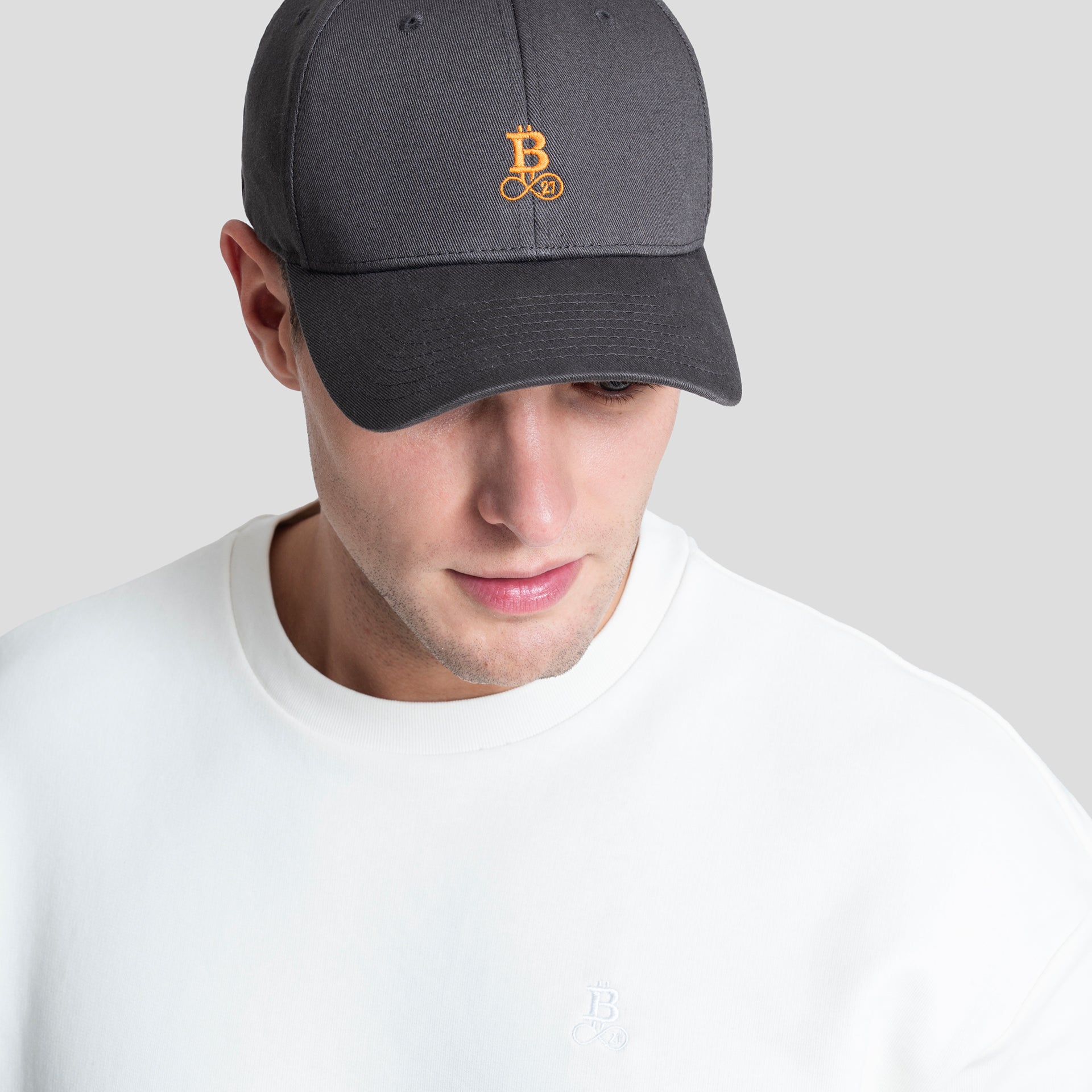 Bitcoin Cap grau aus Bio Baumwolle mit orangefarbenem Bitcoin21 Logo, Snapback Cap in Einheitsgröße am Model getragen