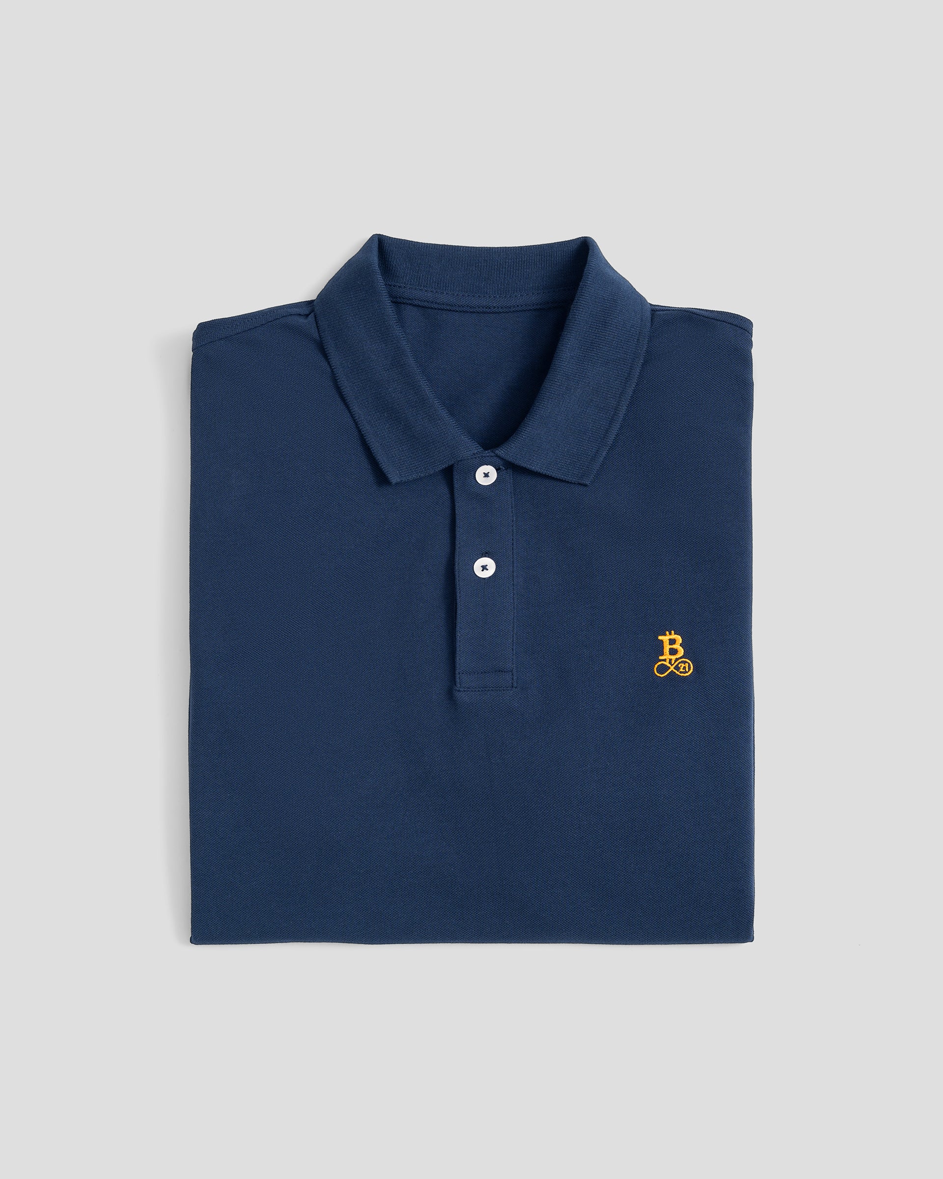 Bitcoin Poloshirt navy für Herren aus Bio Baumwolle mit orangefarbenen gesticktem Bitcoin21 Logo, klassisches Poloshirt zusammengefaltet vor hellem Hintergrund