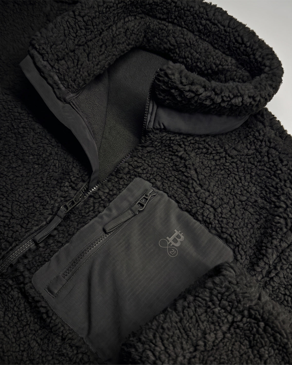 Bitcoin Sherpa Jacket Privacy in Black, detail of collar and chest pocket with tone-on-tone printed Bitcoin21 logo