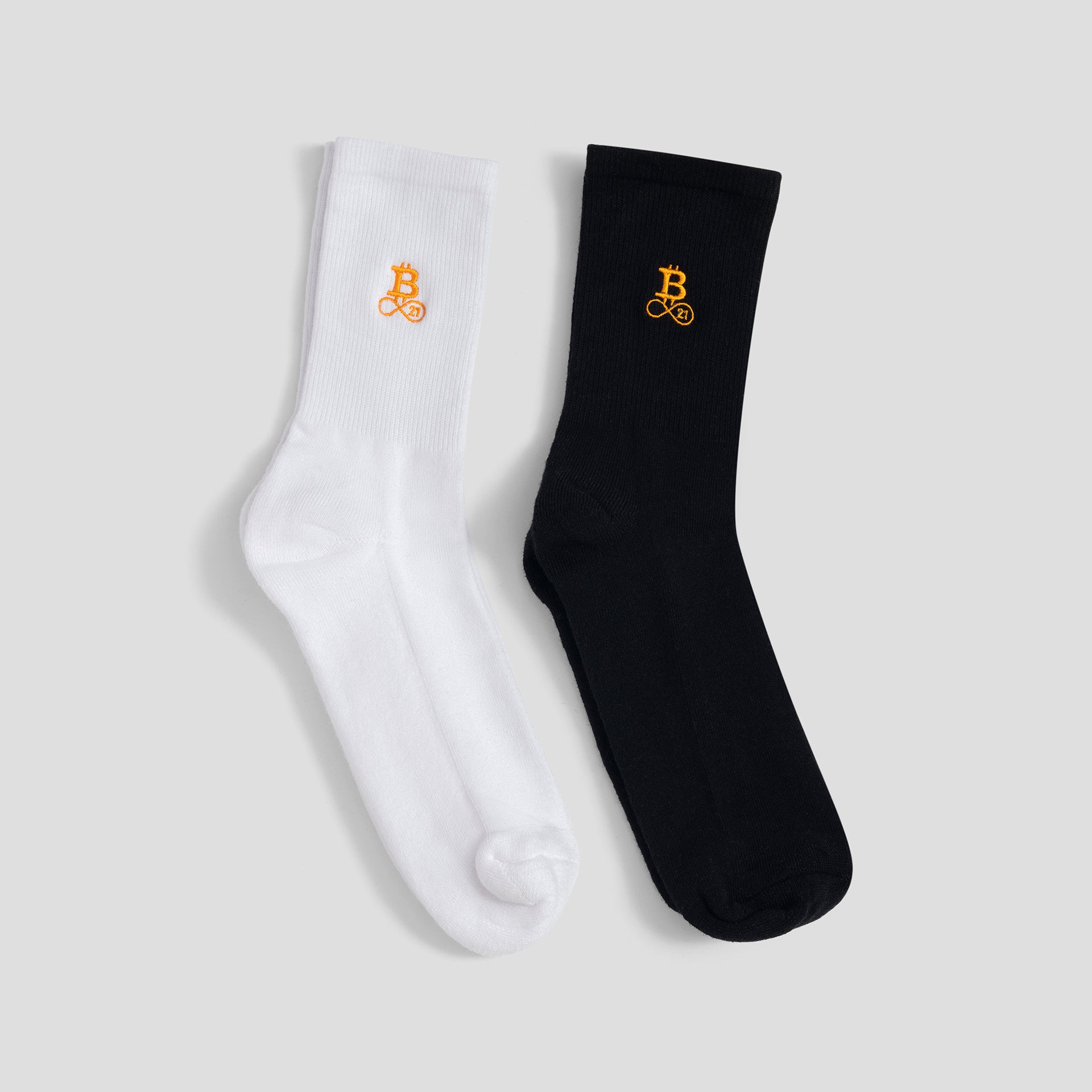 Bitcoin Socken im Doppelpack in Weiß und Schwarz mit orangefarbenem Bitcoin21 Logo auf dem Schaft, klassische Crew Socken freigestellt vor hellem Hintergrund