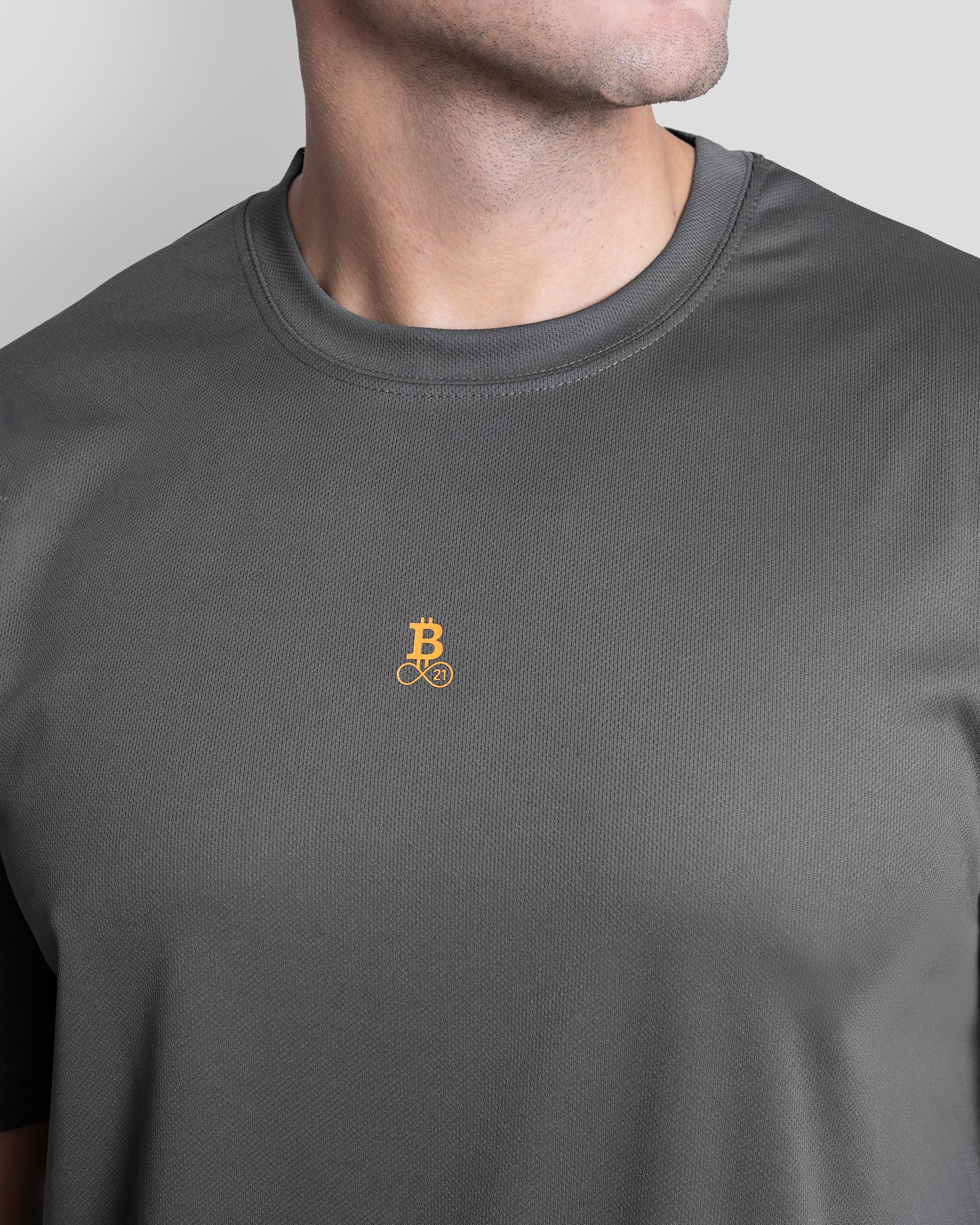 Bitcoin Sportshirt grau für Herren, Nahaufnahme des orangefarbenen Bitcoin21 Logos auf der Brust und der strukturierten Funktionsfaser