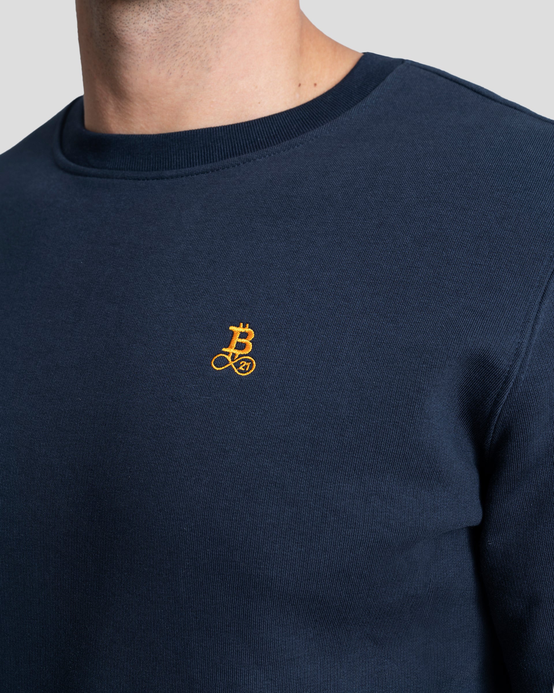 Bitcoin Sweatshirt navy für Herren aus schwerem Bio Baumwollmix, Nahaufnahme des gestickten orangefarbenen Bitcoin21 Logos auf der Brust