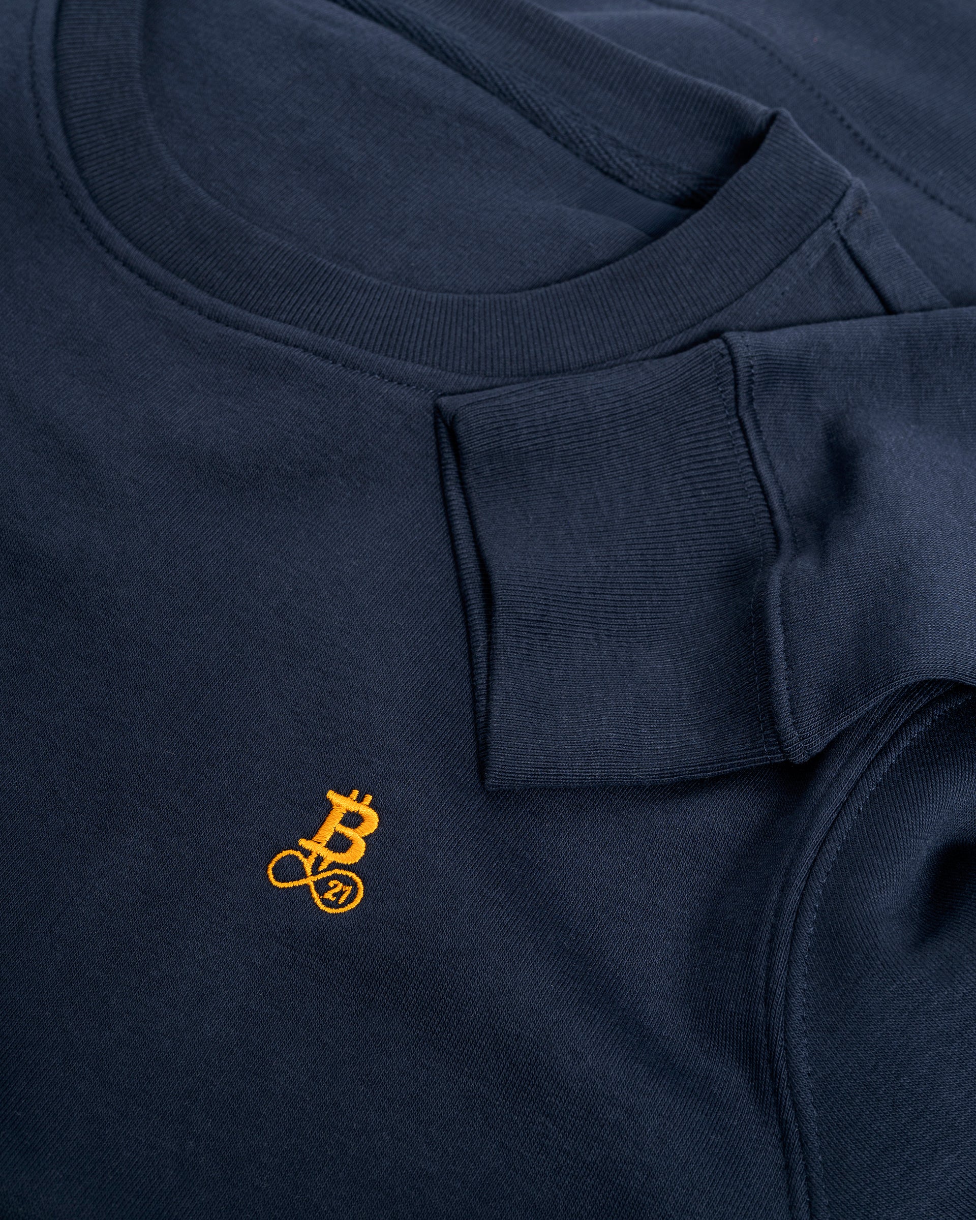 Bitcoin Sweatshirt navy für Herren aus schwerem Bio Baumwollmix, Detailaufnahme von Rundhalsausschnitt, Ärmelbündchen und gesticktem orangefarbenen Bitcoin21 Logo