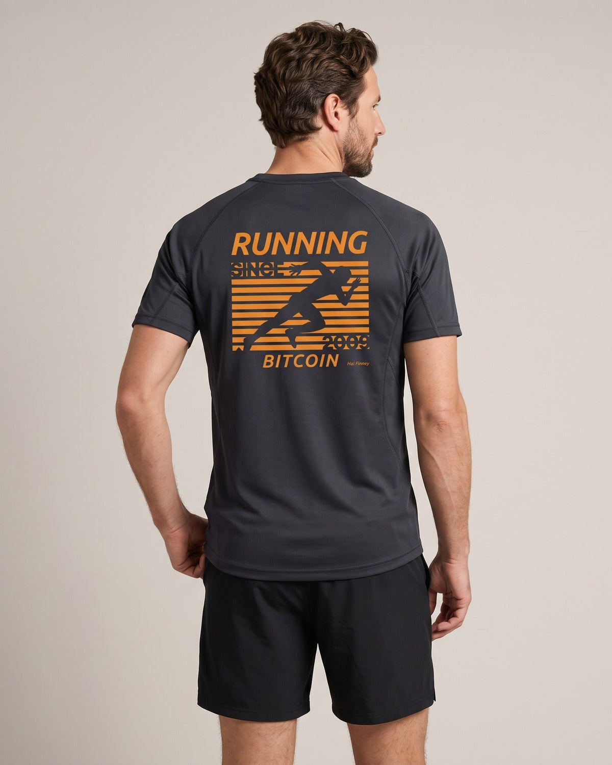 Man wearing the Bitcoin Running Shirt Hal Finney in Charcoal, back print with an orange runner, RUNNING BITCOIN, 2009 and Hal Finney