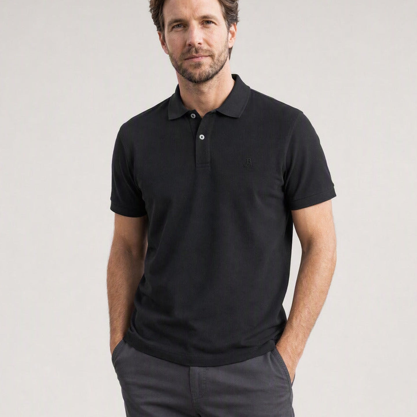Hombre con el Polo Bitcoin Privacy - Negro de algodón piqué — logo Bitcoin21 bordado tono sobre tono, manos en los bolsillos del pantalón