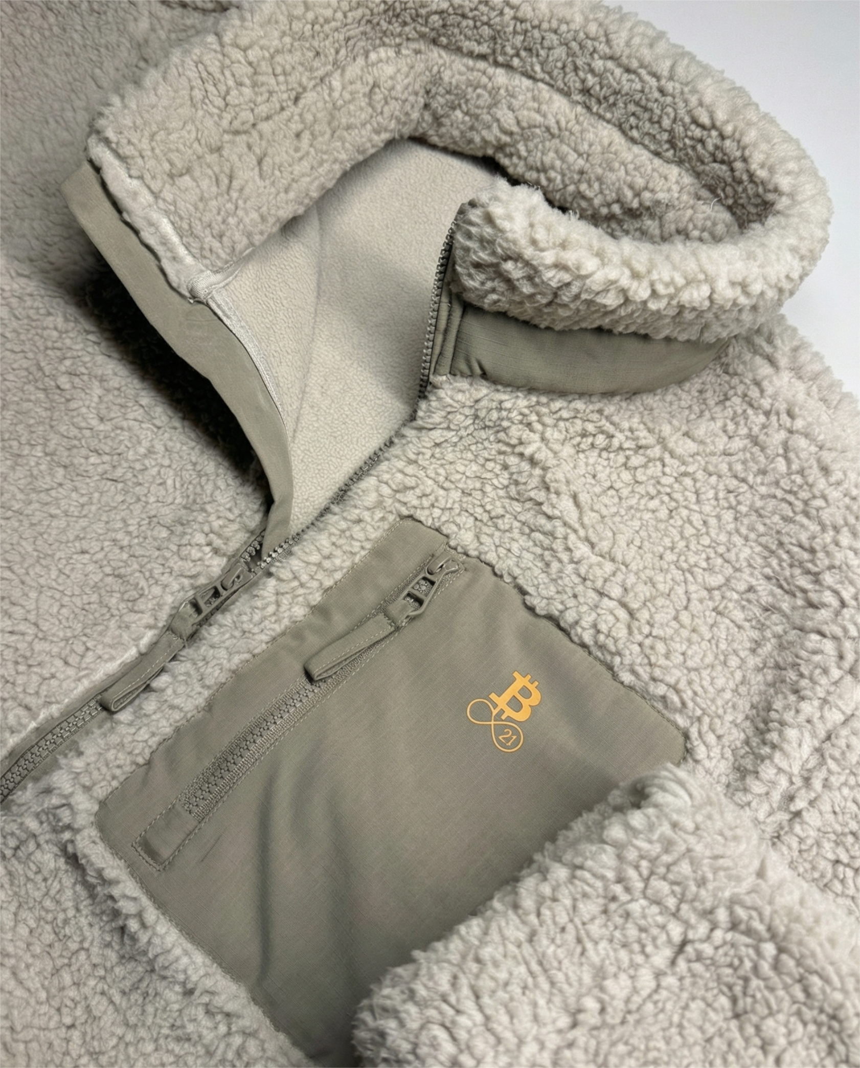 Bitcoin Sherpa Jacke Beige Teddy-Fleece – Detail der Brusttasche mit Reißverschluss und Bitcoin Logo