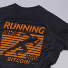 Bitcoin hardloopshirt Hal Finney in donkergrijs, detailopname van de rugprint met oranje hardloper, RUNNING BITCOIN, 2009 en Hal Finney