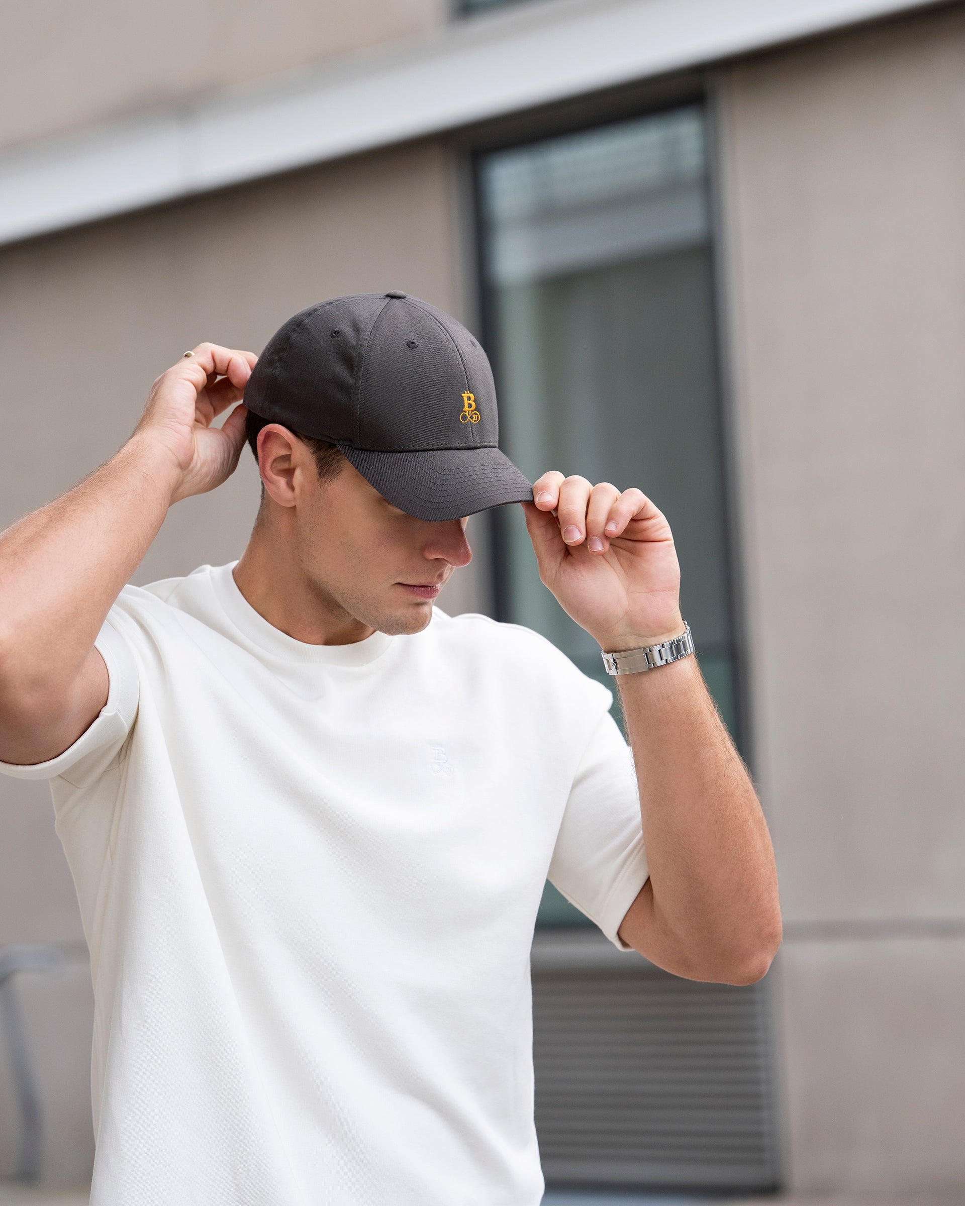 Bitcoin Cap grau aus Bio Baumwolle mit orangefarbenem Bitcoin21 Logo, Lifestyle Aufnahme mit Model, das die Cap im urbanen Umfeld trägt