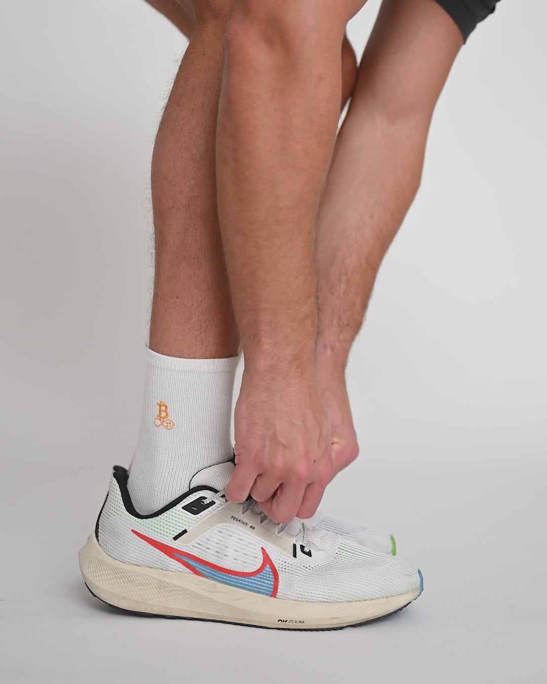 Model trägt Bitcoin21 Bitcoin Socken mit Sportschuhen und richtet Socken und Schuhe