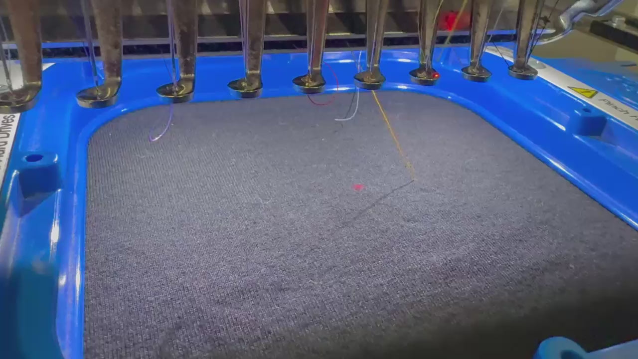 Detailvideo der gestickten orangefarbenen Bitcoin21 Logo Stickerei auf navy Stoff, hochwertige Bitcoin Kleidung aus Bio Baumwolle