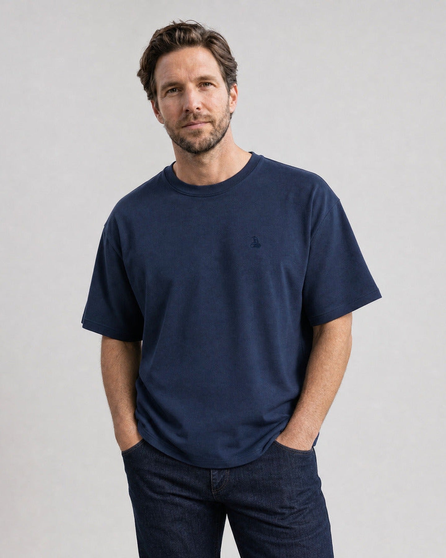 Homme portant le T-shirt oversize Bitcoin Privacy - Marine — logo Bitcoin21 brodé ton sur ton sur la poitrine, mains dans les poches