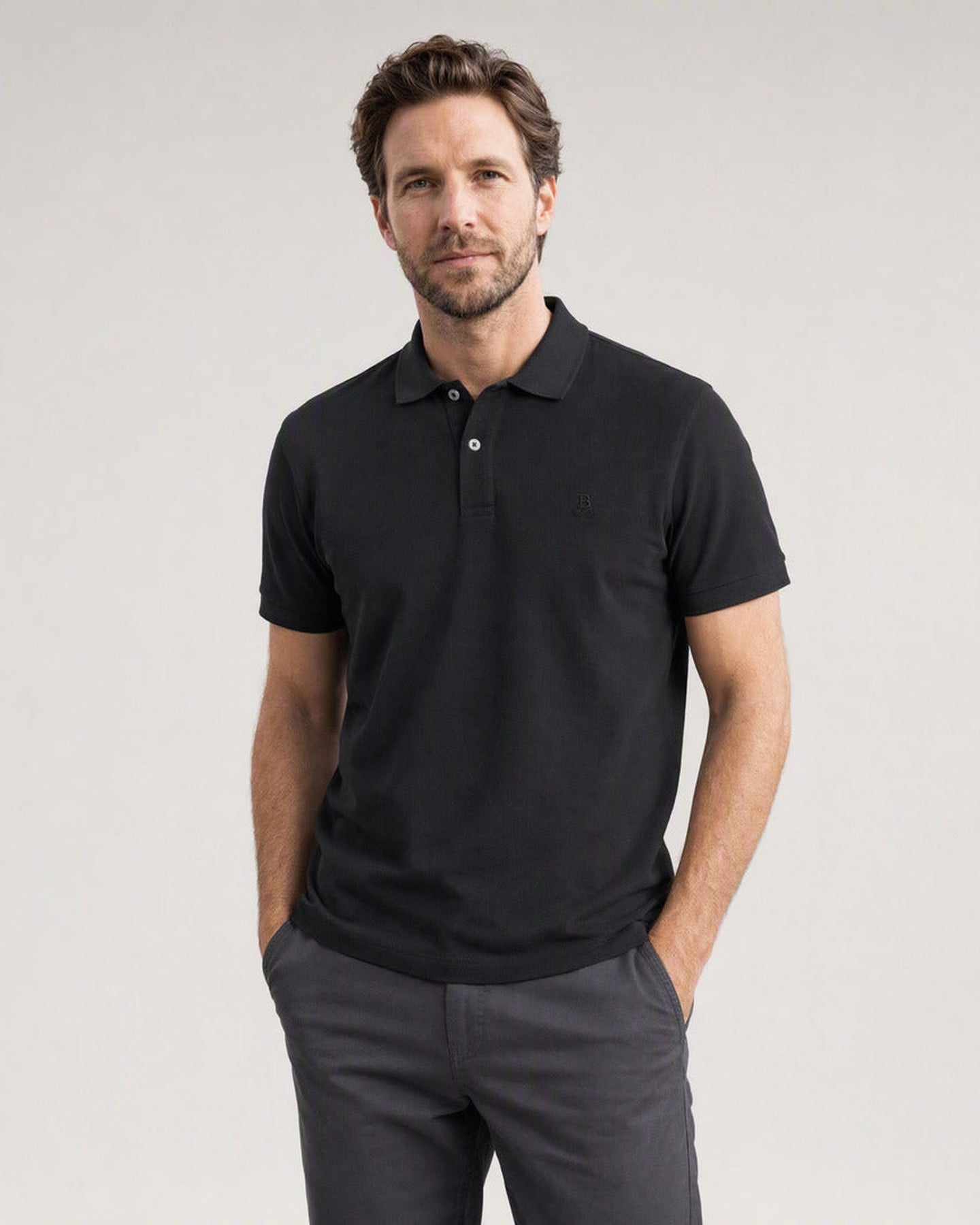 Hombre con el Polo Bitcoin Privacy - Negro de algodón piqué — logo Bitcoin21 bordado tono sobre tono, manos en los bolsillos del pantalón